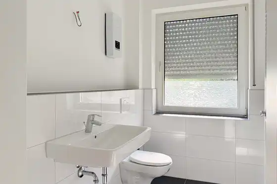 Badezimmer frisch saniert. Hell, modern, weiß, mit Fenster über der Toilette